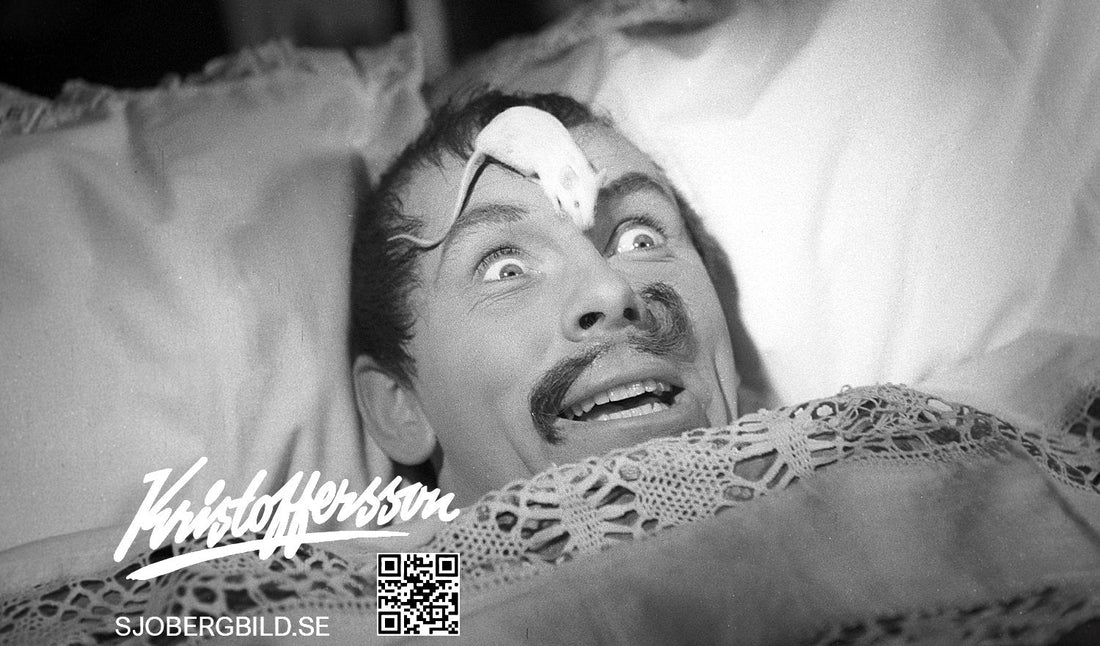 Nils Poppe ligger i en säng med en vit råtta på pannan i filmen Ballongen från 1946.